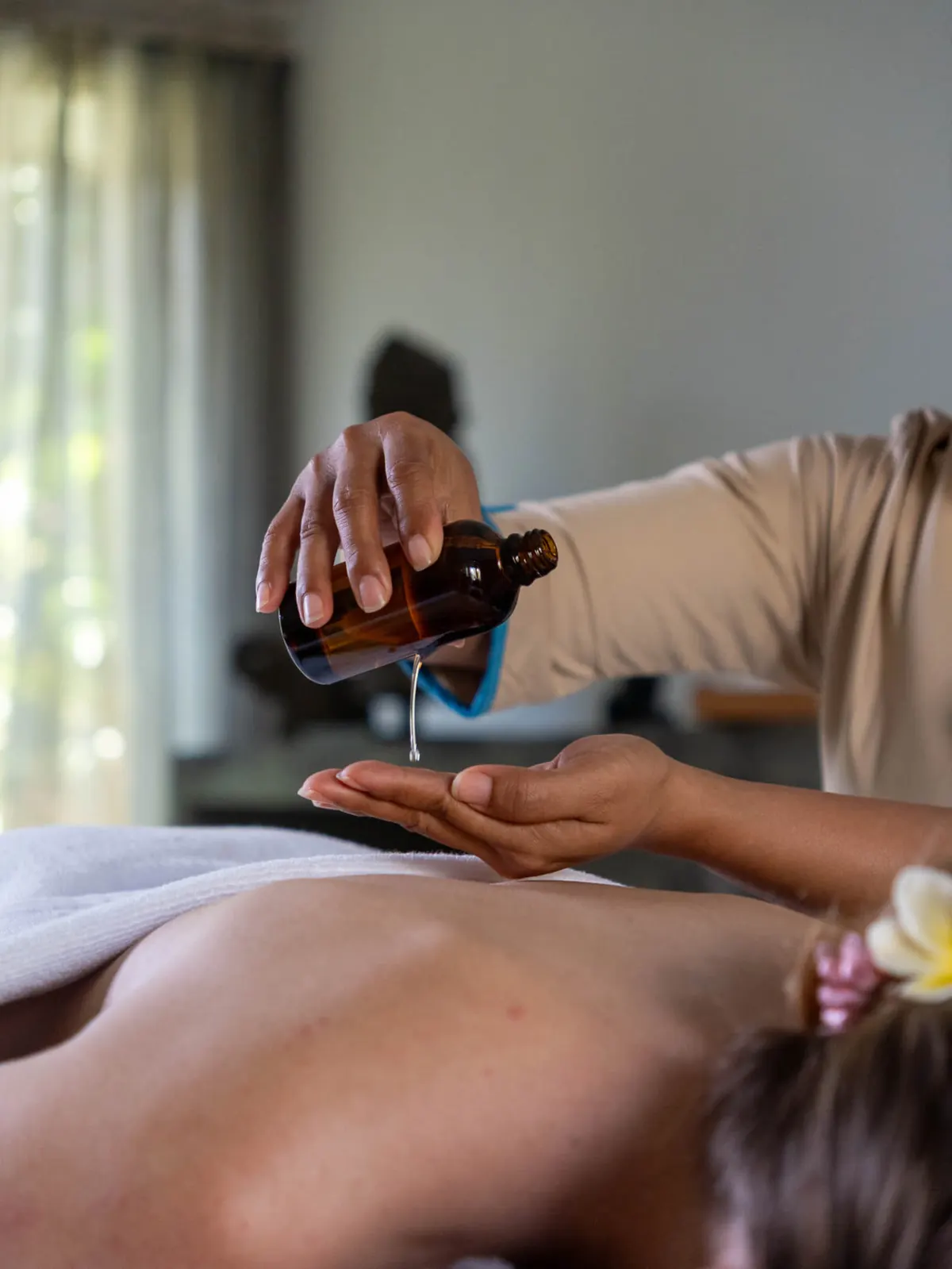 A Raha therapist pouring massage oil before a treatment